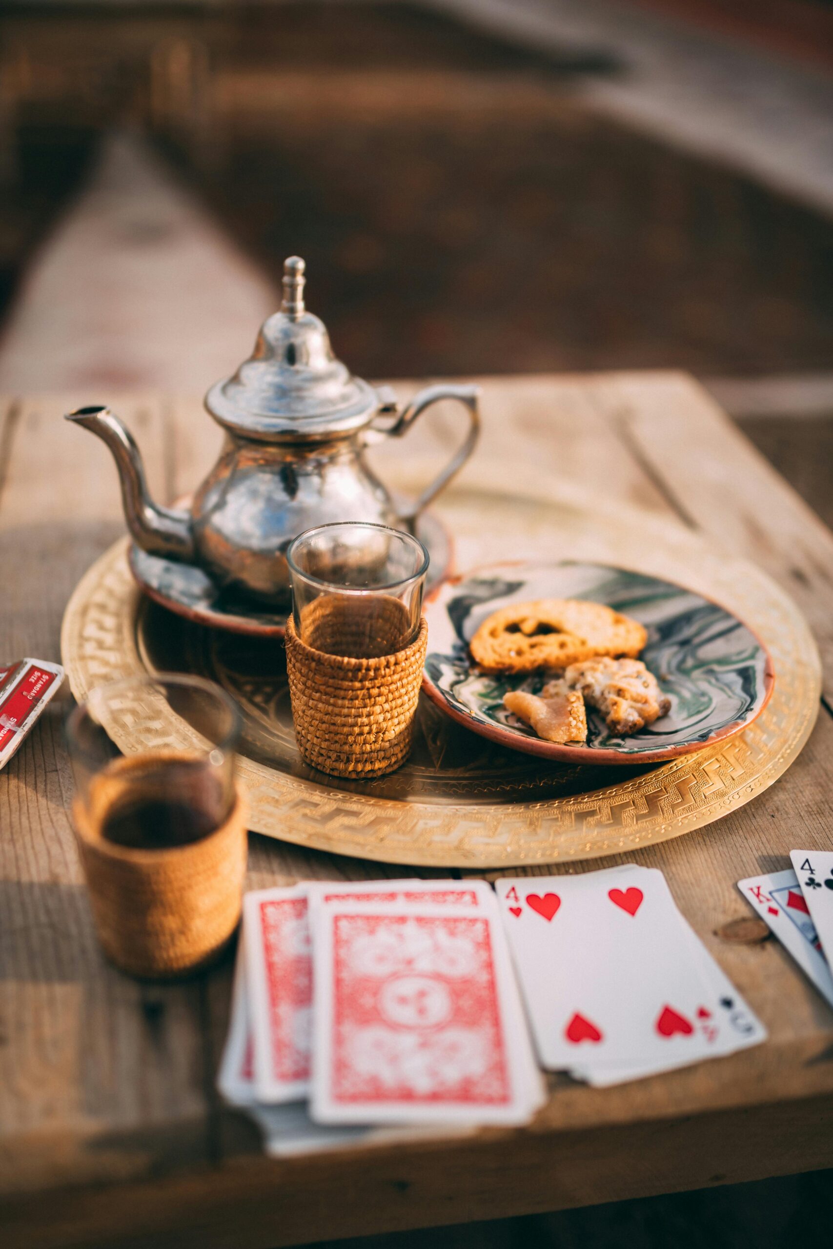 Authentic Moroccan tea setup with playing cards on a rustic wooden table in Marrakesh.